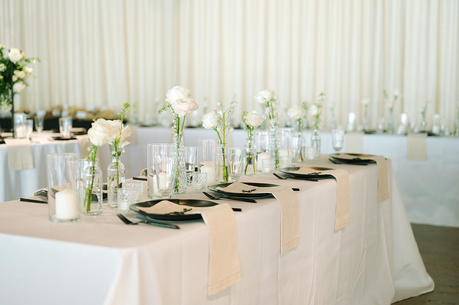 Details of a table setting with white linens and black dishes at a wedding reception