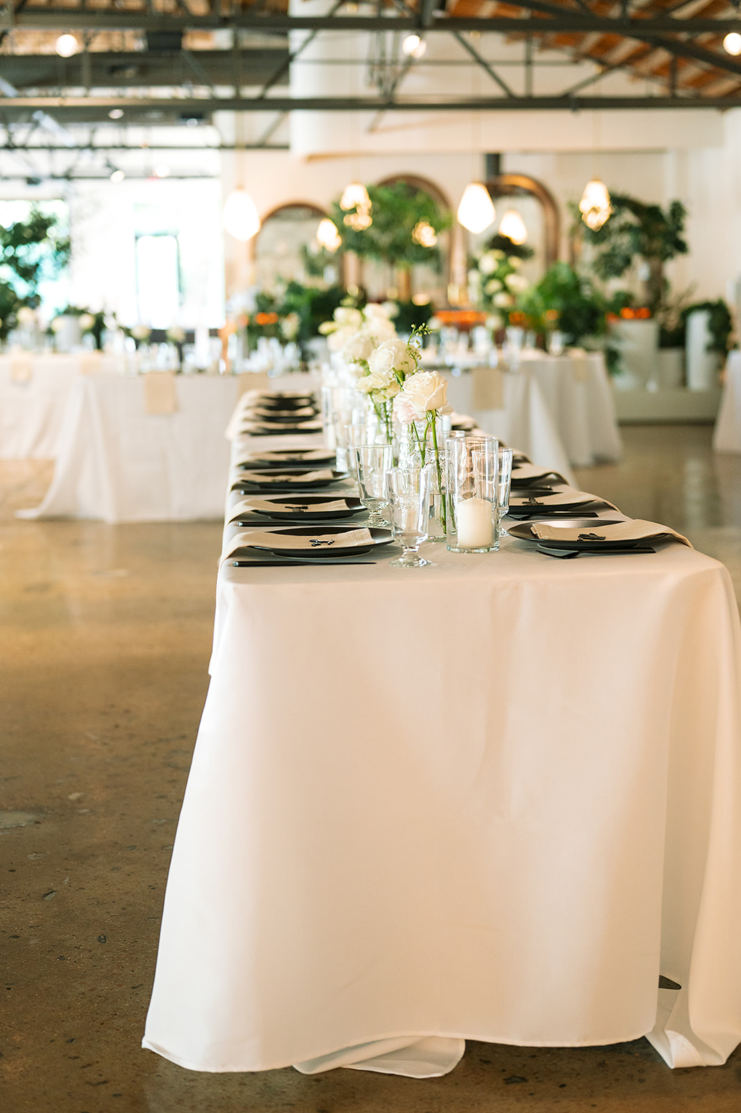 Details of the reception table setup with white flowers and linens at Saint Elle wedding venue