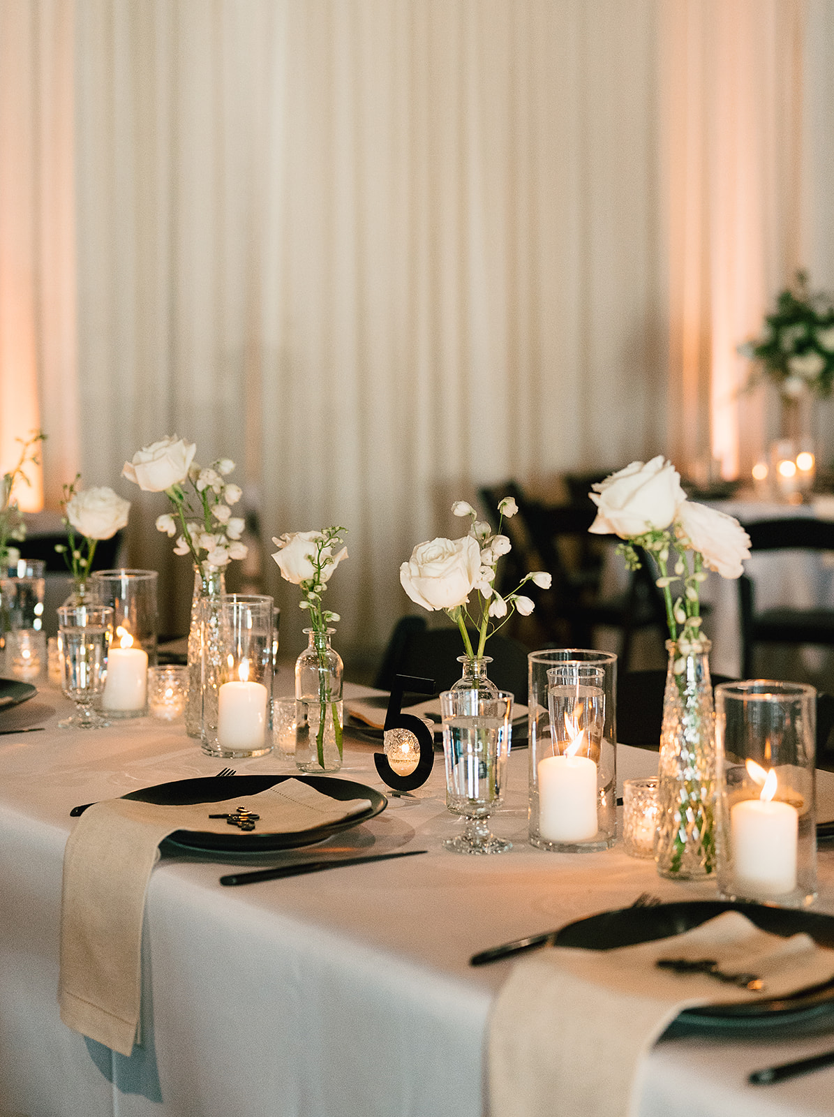 Details of a table setting with white flowers and white linens at a Saint Elle Wedding