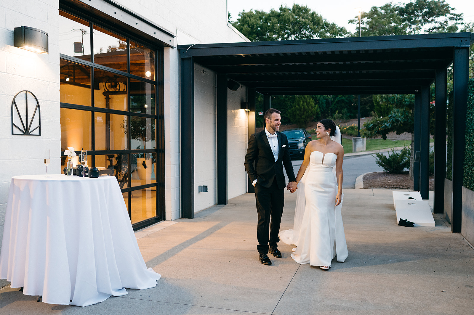 Newlyweds walk through the patio at sunset holding hands at Saint Elle Wedding venue