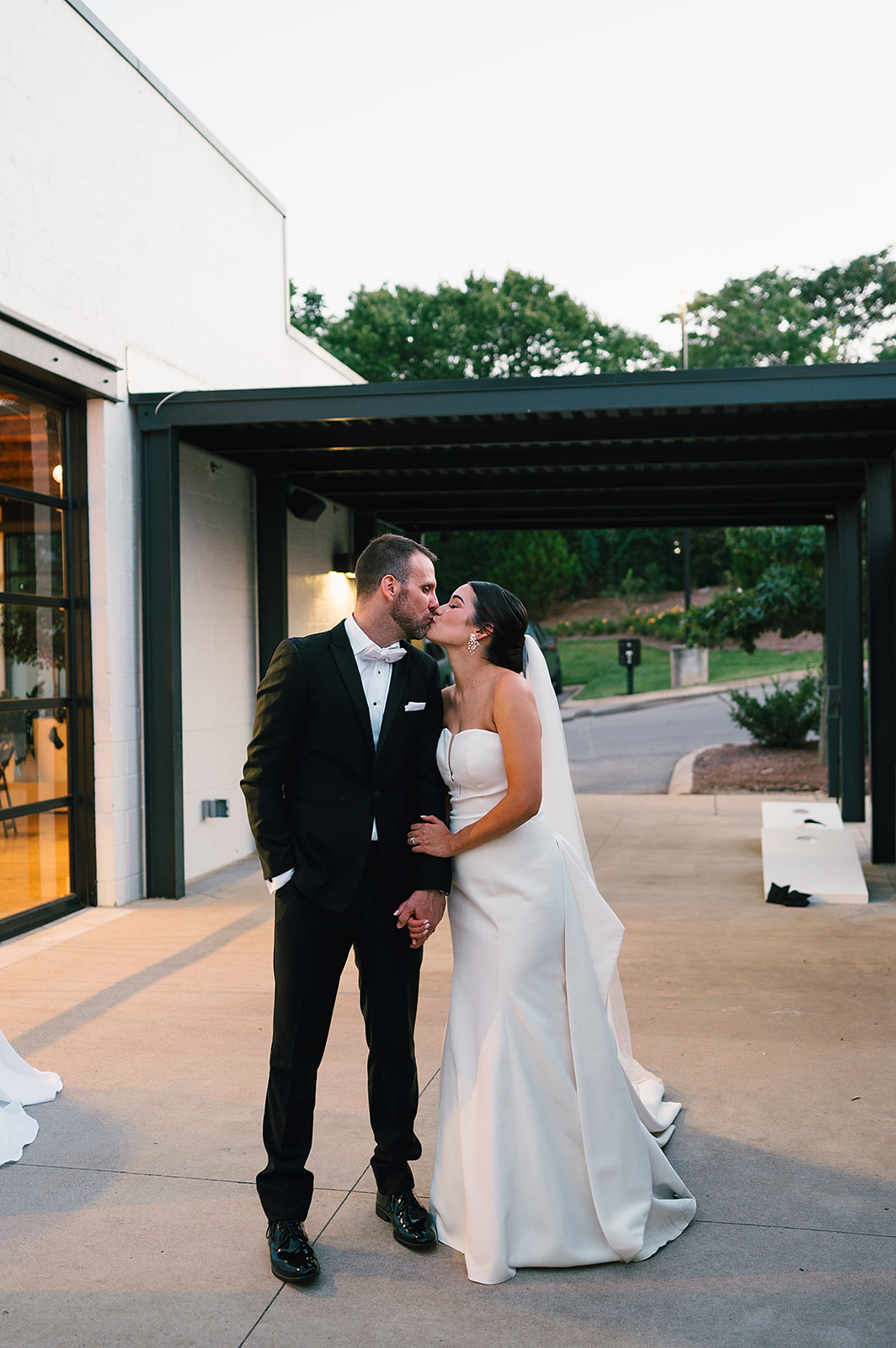 Newlyweds kiss and hold hands while walking on the patio of Saint Elle Wedding venue