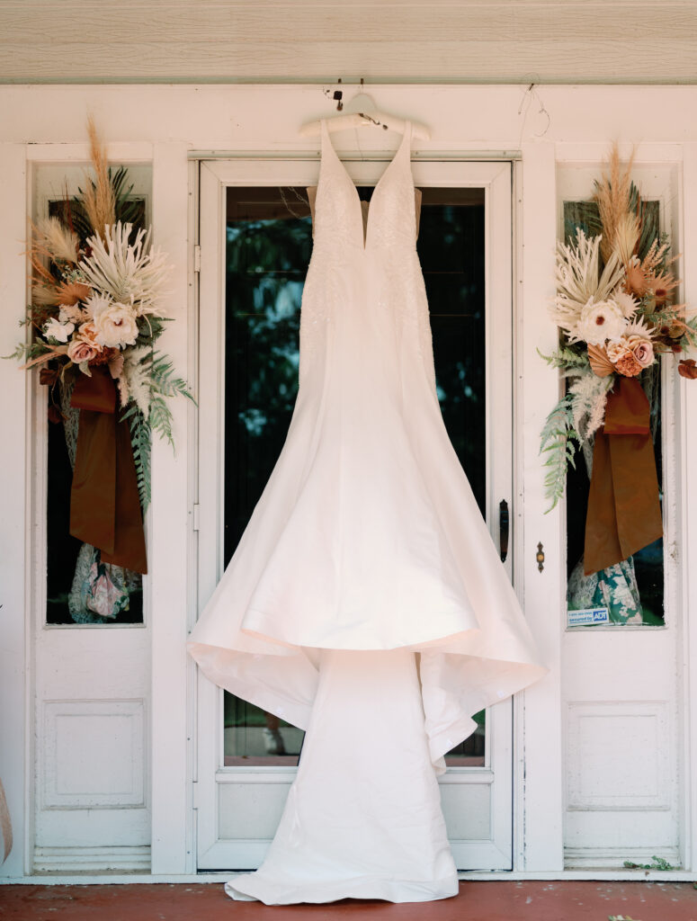 Simple wedding gown hanging on front porch.