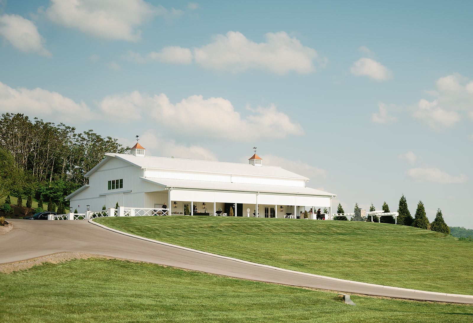 A view of the beautiful The White Dove Barn wedding venue on a grassy hill